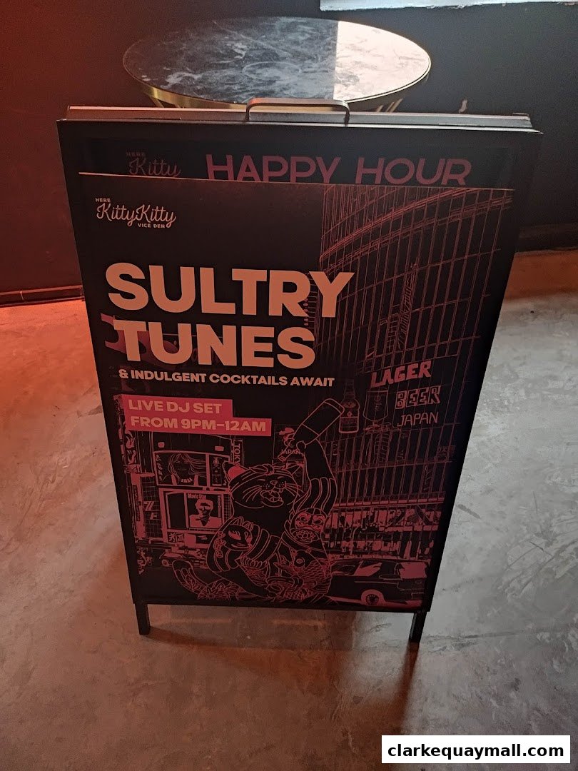 A-frame sign advertising 'Sultry Tunes' and 'Happy Hour' with a live DJ set.