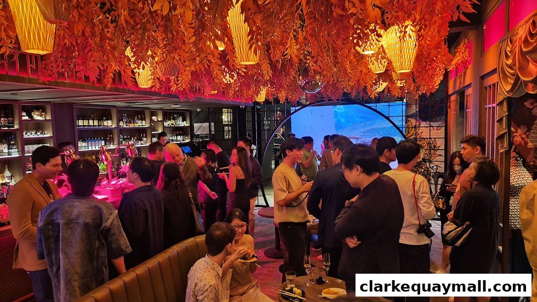 A lively cocktail lounge with people socializing under a canopy of red leaves and hanging lanterns.