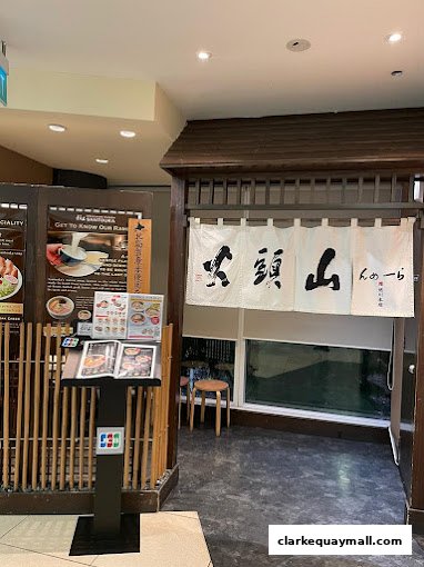 The entrance to Hokkaido Ramen Santouka, featuring a traditional Japanese noren curtain and a display menu.