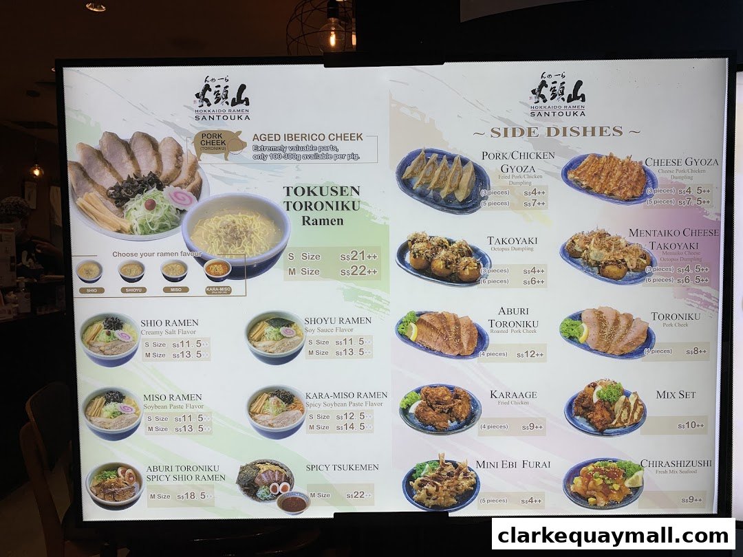 A brightly lit menu board showcasing various ramen dishes and side dishes from Hokkaido Ramen Santouka.