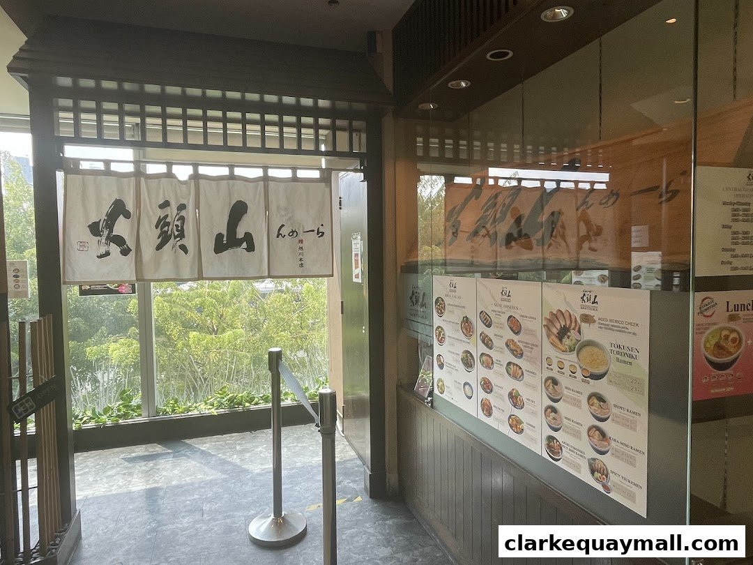 Entrance to Hokkaido Ramen Santouka with Japanese noren curtains and a displayed menu.