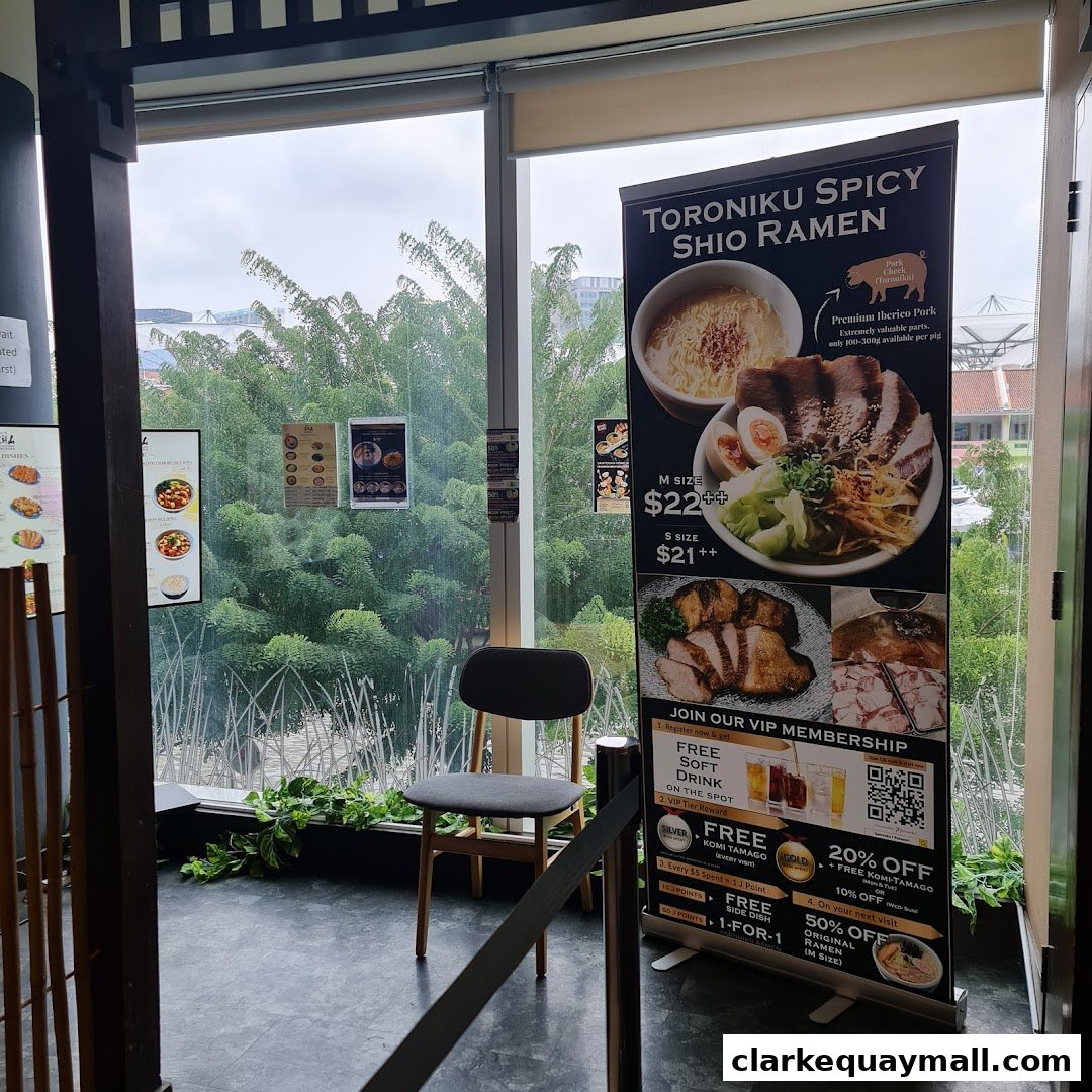 A promotional banner for Toroniku Spicy Shio Ramen is displayed near a window with a chair.