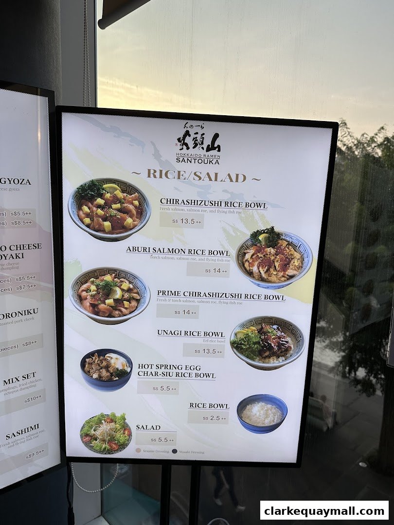 A brightly lit menu board displaying various rice bowls and salads from Hokkaido Ramen Santouka.