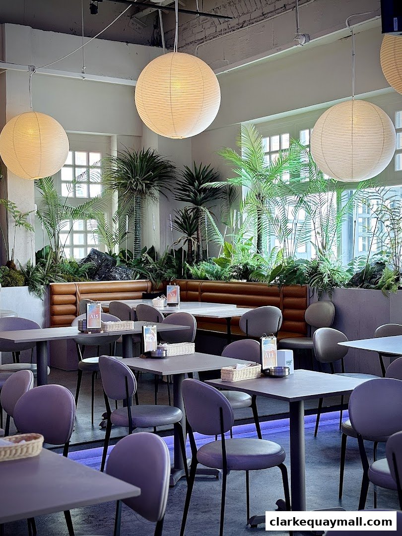 Interior of a cafe with tables, chairs, plants, and large paper lanterns.