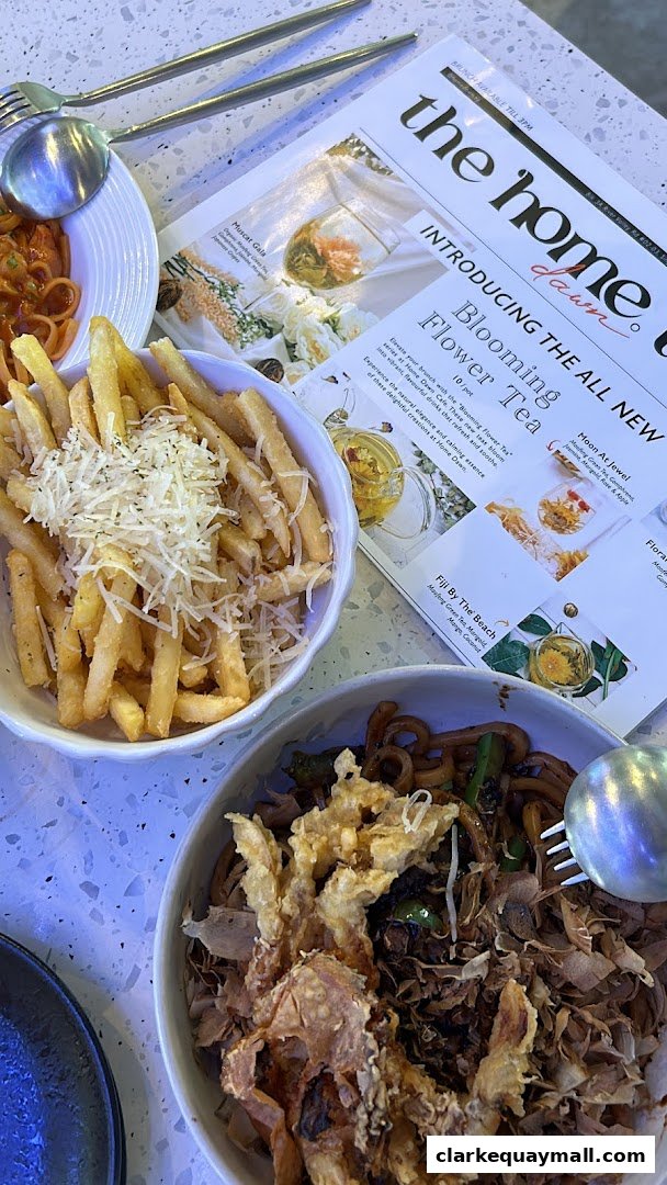 A table setting with bowls of fries and noodles, and a menu featuring flower teas.