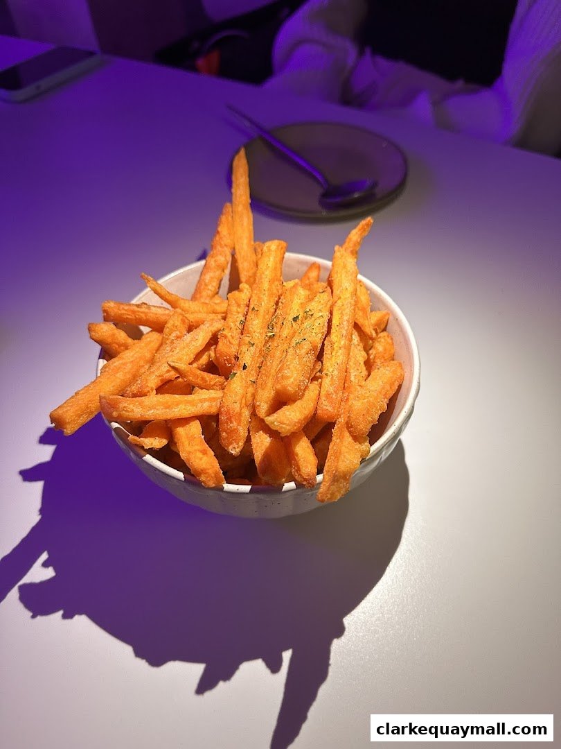 A bowl of crispy sweet potato fries seasoned with herbs, served on a table.