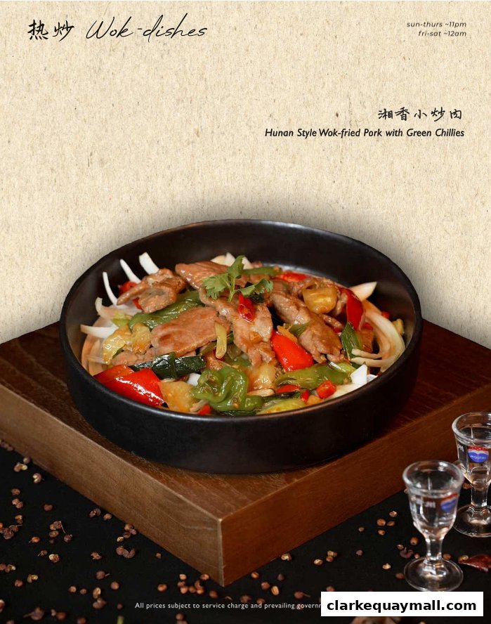 A close-up of Hunan Style Wok-fried Pork with Green Chillies served in a black bowl.
