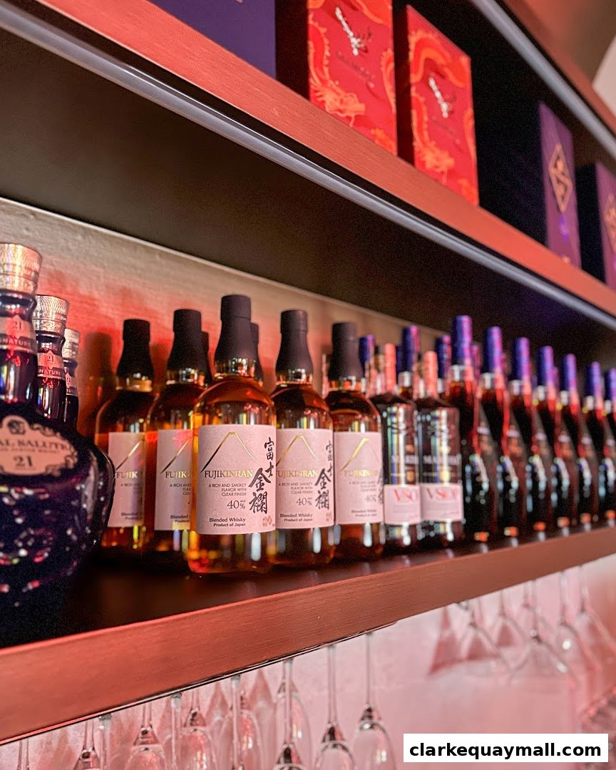 Shelves stocked with bottles of whisky and decorative boxes, with wine glasses hanging below.