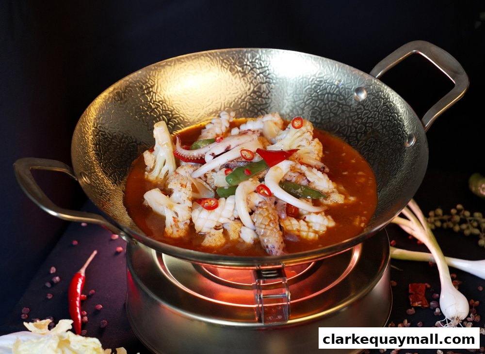 A close-up shot of a flavorful squid and cauliflower dish served in a golden wok.