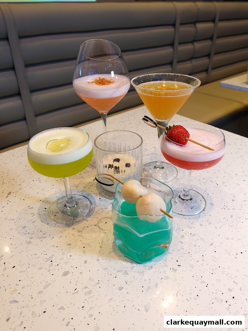 A selection of colorful cocktails garnished with fruit and served on a speckled countertop.