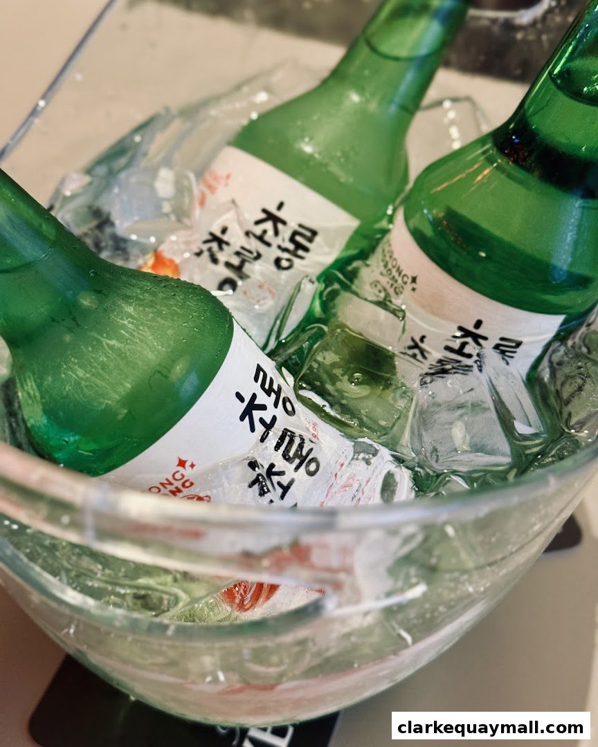 Three green bottles of soju chilling in a glass bowl filled with ice.