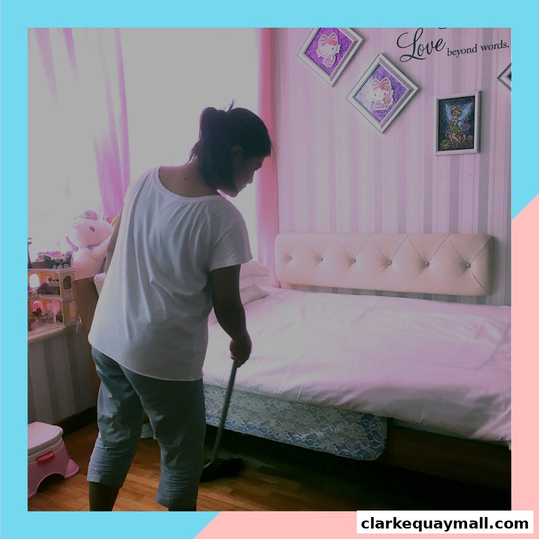 A person is sweeping a bedroom with a bed and decorative wall art.