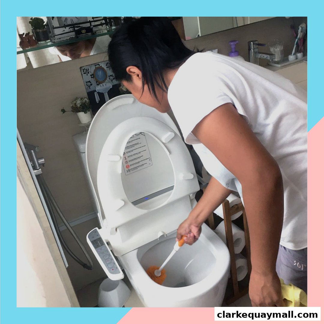 A person is cleaning a modern toilet with a toilet brush.