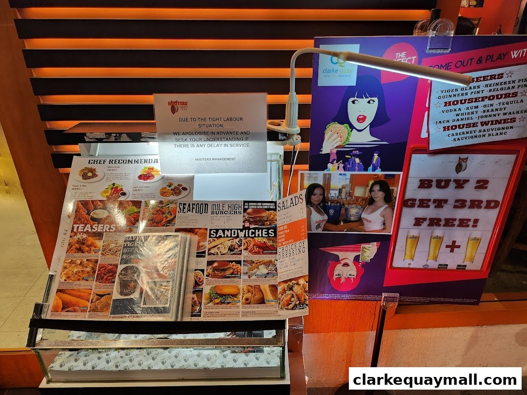 A display of Hooters' menu items, drinks, and promotions, including a labor shortage notice.