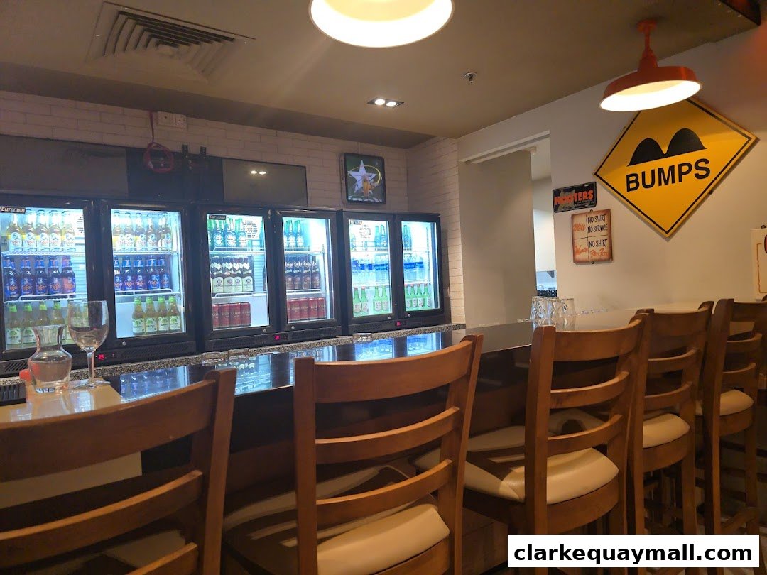 Interior view of a Hooters restaurant with a bar, refrigerators stocked with drinks, and seating.