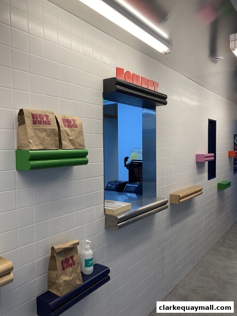 A clean, modern food counter with branded paper bags and a service window.