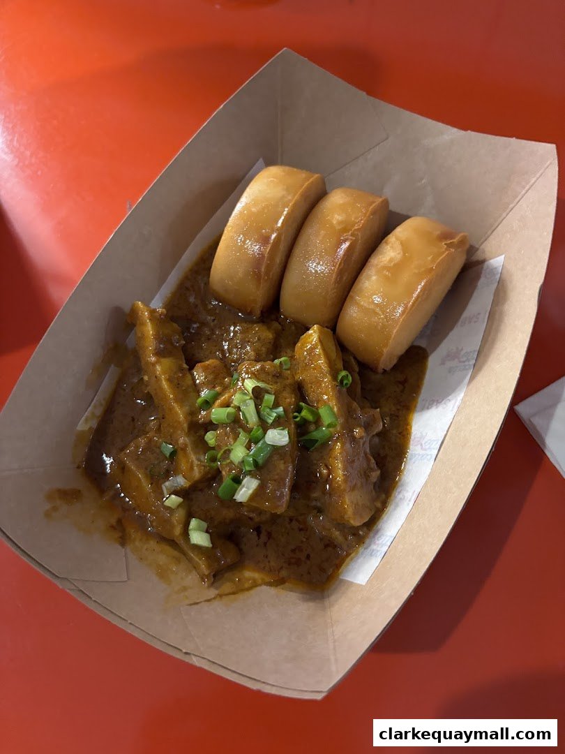 A serving of savory curry with fried buns and chopped green onions.