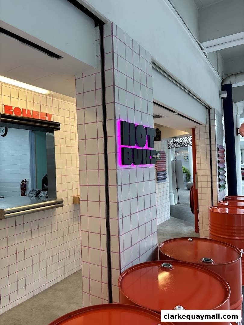 The exterior of a shop called HOT BUNS with a tiled facade and neon signage.