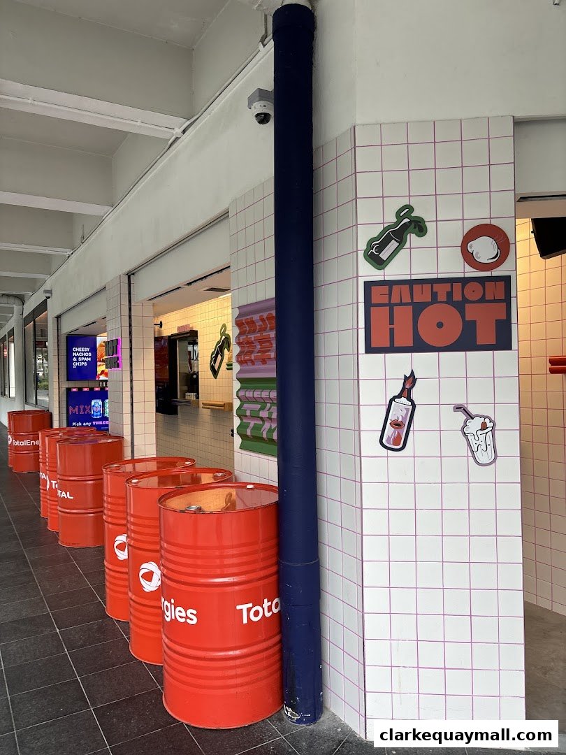 The exterior of a shop with red barrels and tiled walls featuring quirky decals.