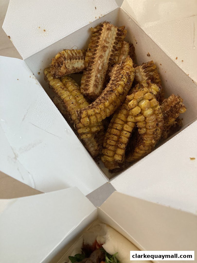 A white takeout box filled with seasoned corn cob pieces.