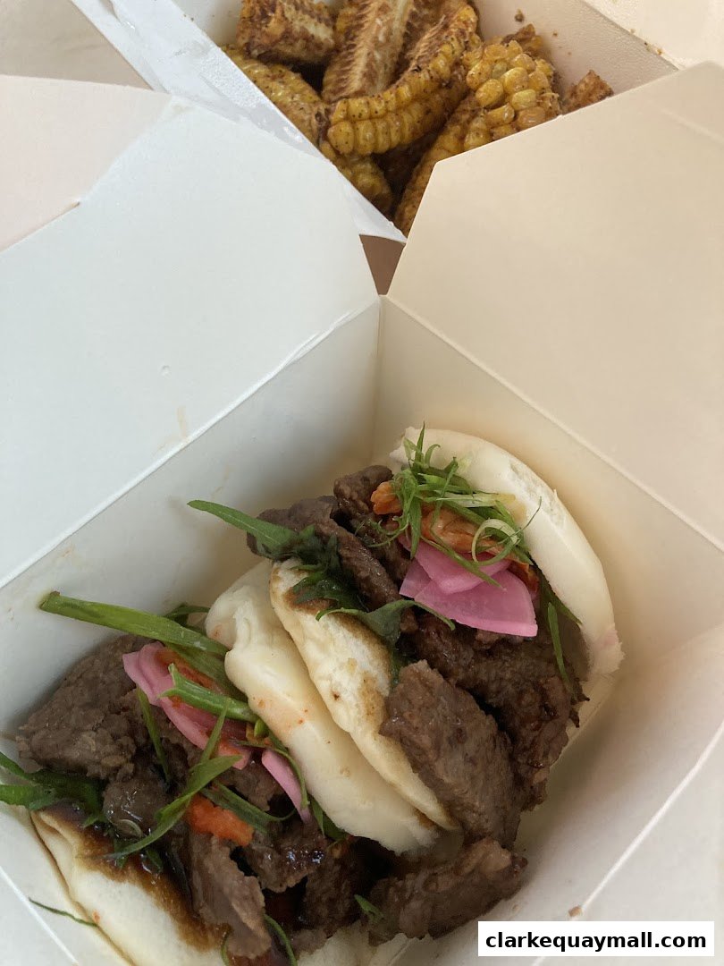 Two takeout boxes filled with delicious food, one with bao buns and beef, the other with corn.