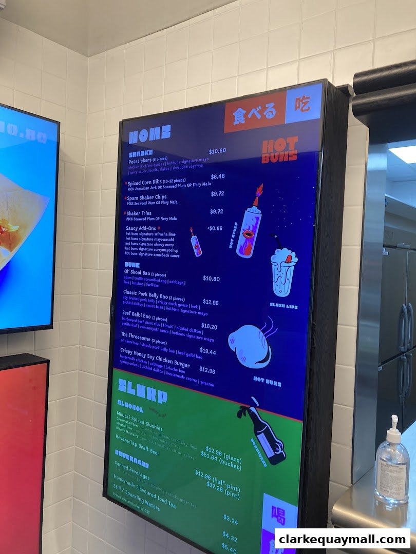 A digital menu board displaying food and drink items with prices for the "HOT BUNS" restaurant.
