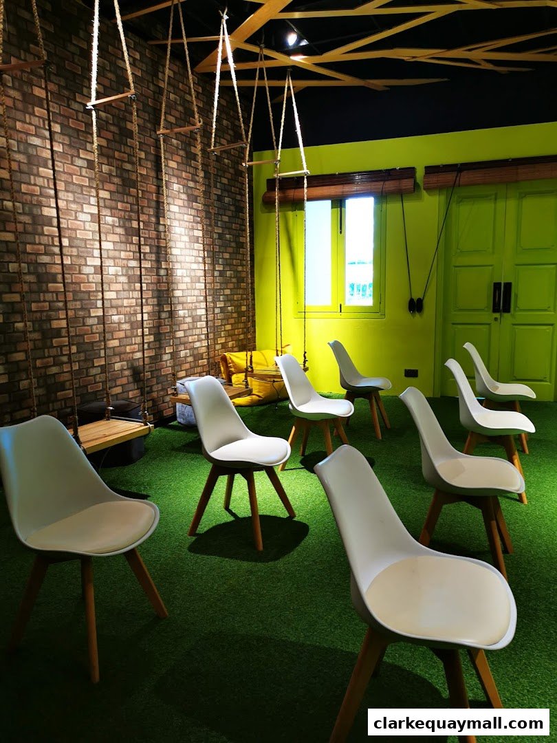 Interior shot of a unique space with swings, chairs, and green turf flooring.