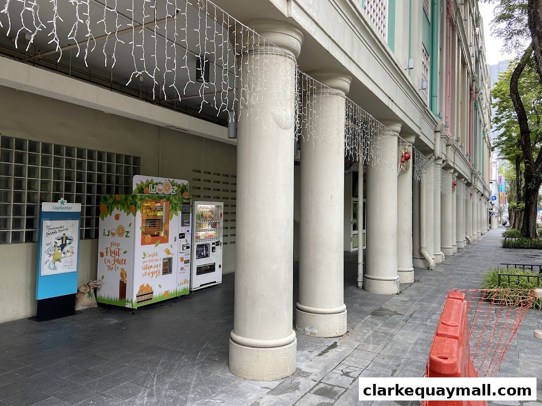 Two juice vending machines, one branded iJooz, are located outside a building with large columns.
