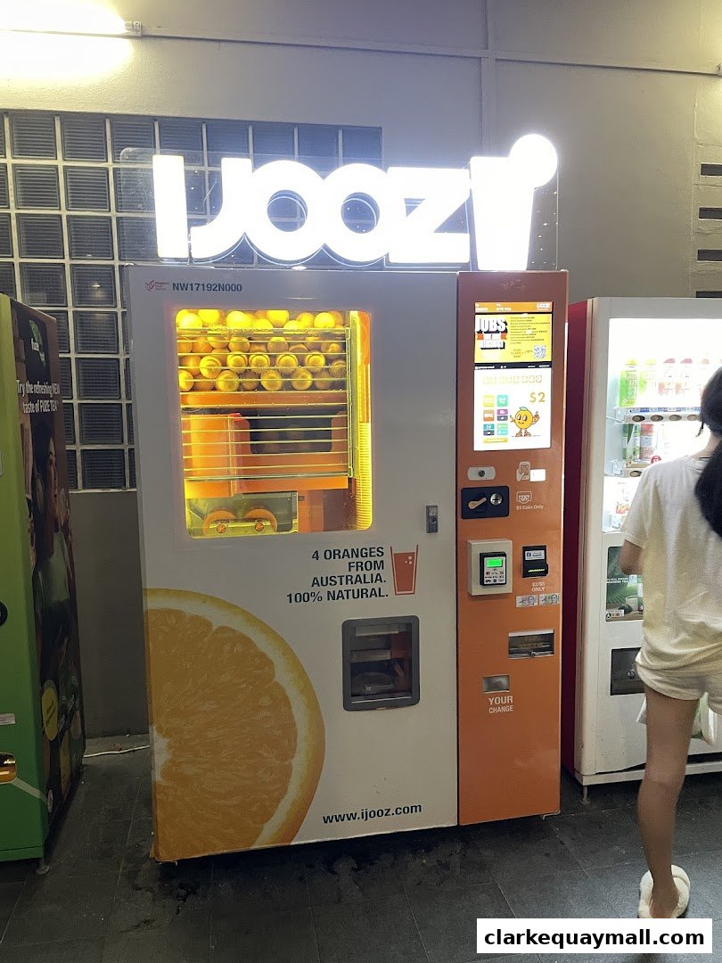 A bright orange juice vending machine with a large orange graphic and the brand name 'iJooz'.
