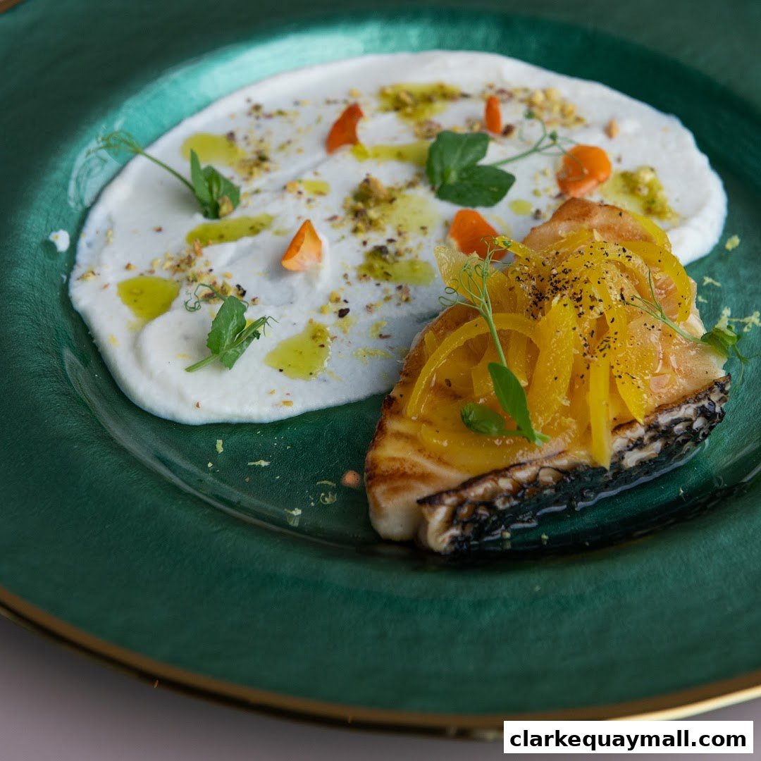 A beautifully plated dish of grilled fish with a creamy puree and citrus garnish.