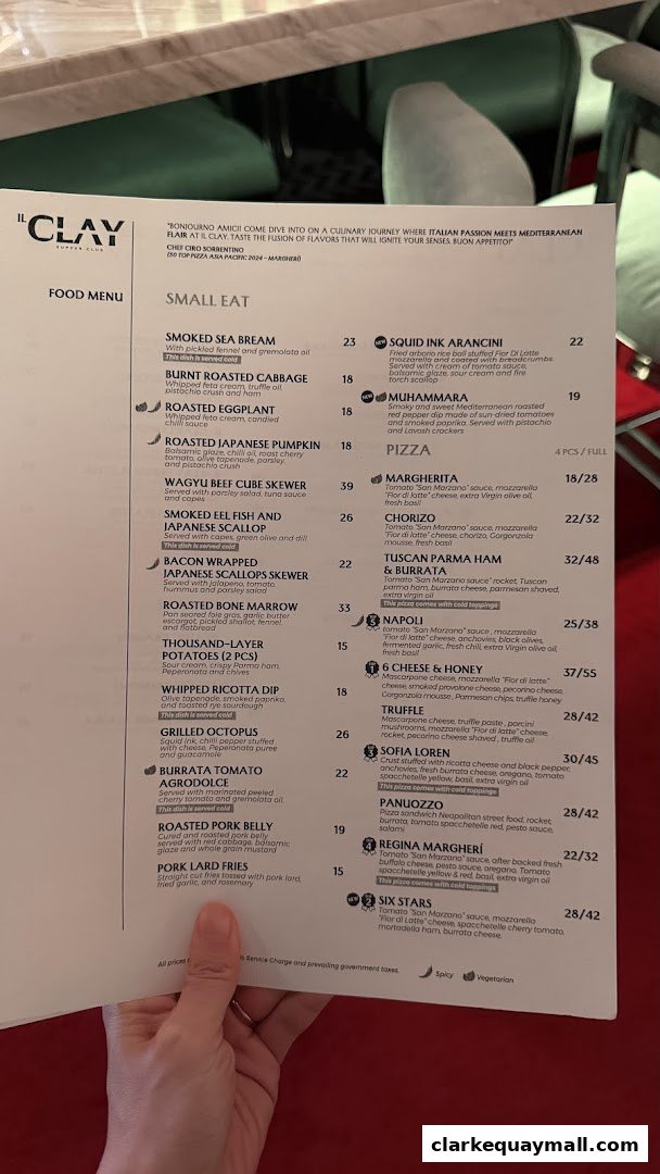 A person's hand holding a food menu from IL CLAY Supper Club.