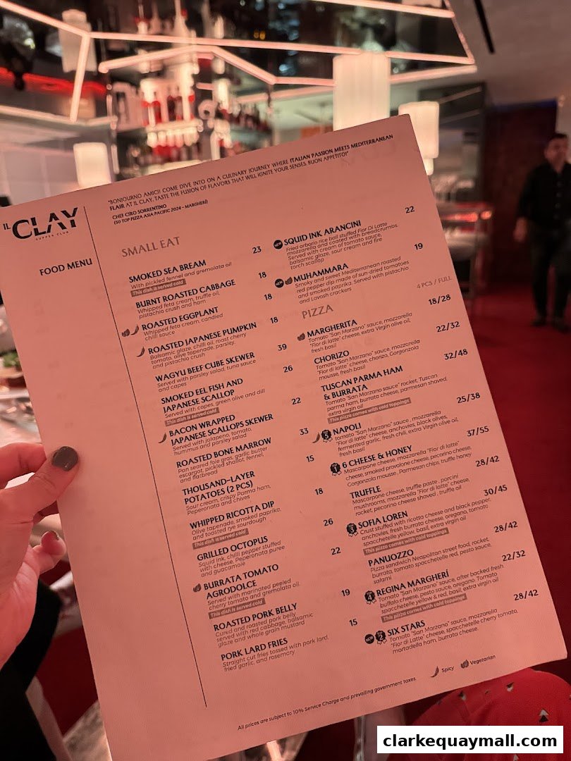 A person holds a food menu from IL CLAY restaurant, showcasing various dishes and prices.