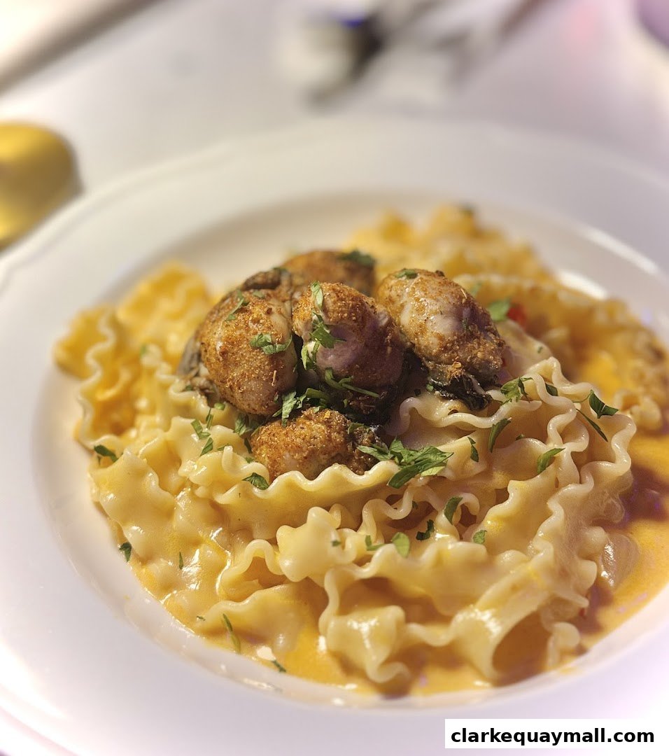 A close-up of pasta with oysters in a creamy sauce, garnished with parsley.