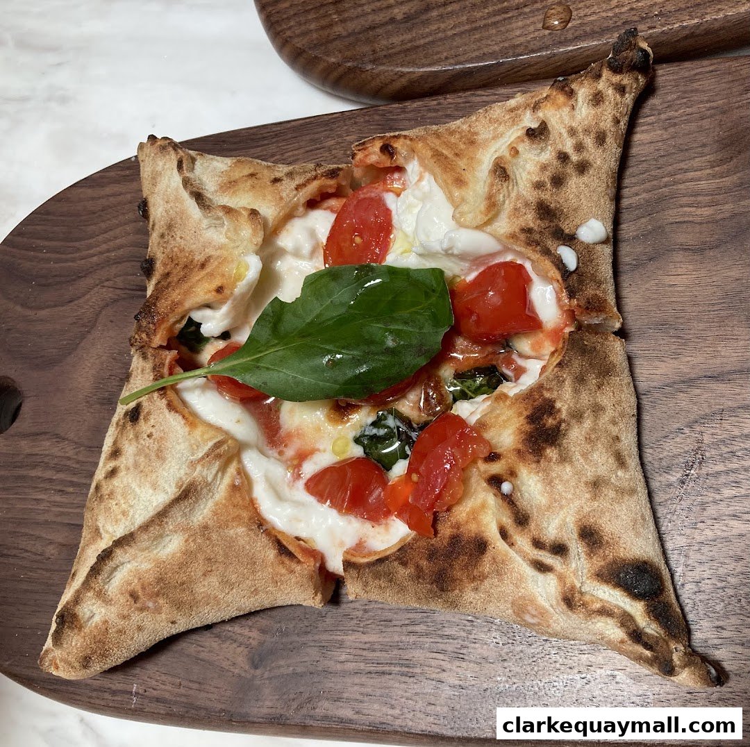A delicious square-shaped pizza with fresh tomatoes, mozzarella, and basil on a wooden board.