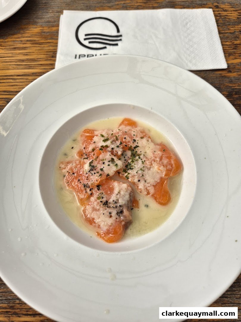 A white bowl of salmon sashimi with sauce and herbs, with an IPPUDO napkin.