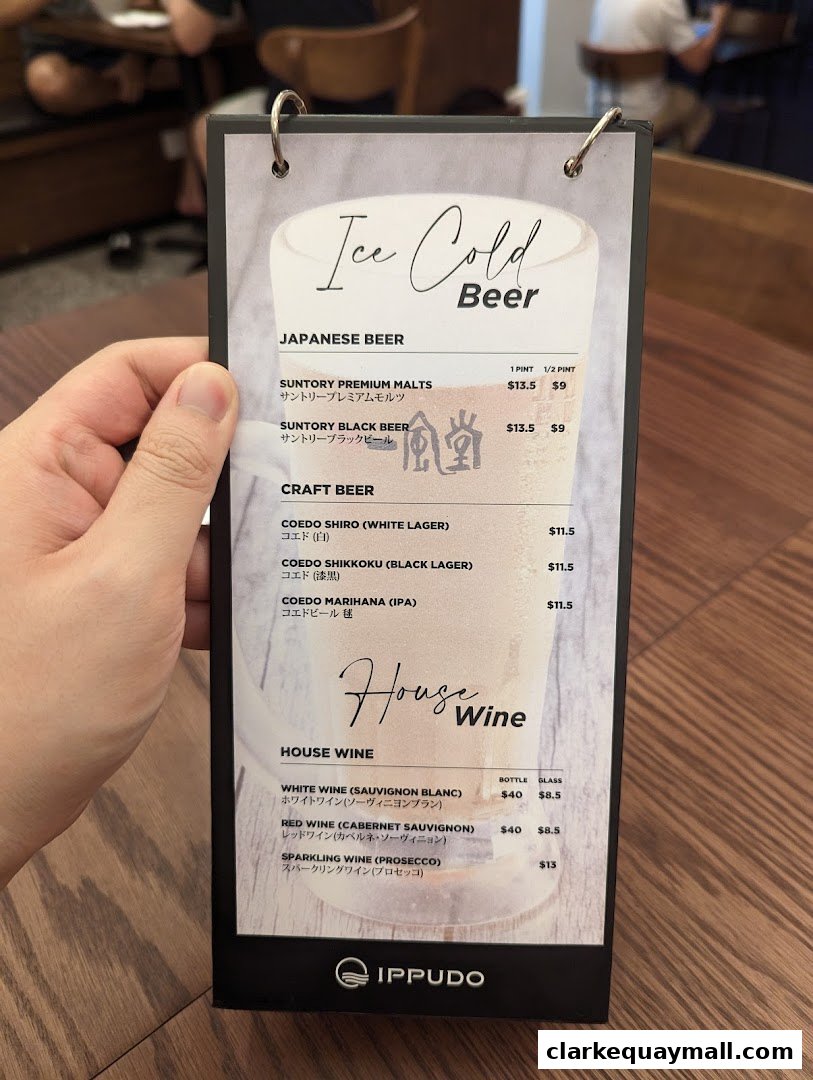 A hand holds a menu featuring Japanese and craft beers, and house wines from IPPUDO.
