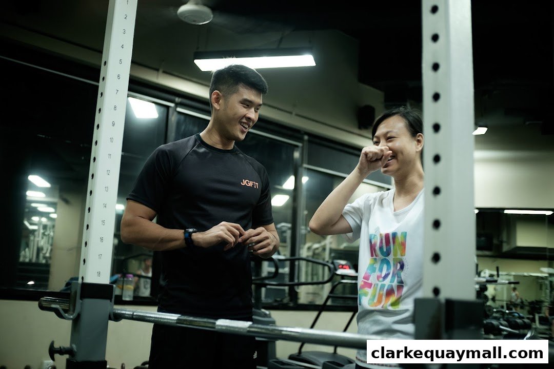 A male trainer and a female client smiling and interacting in a gym.