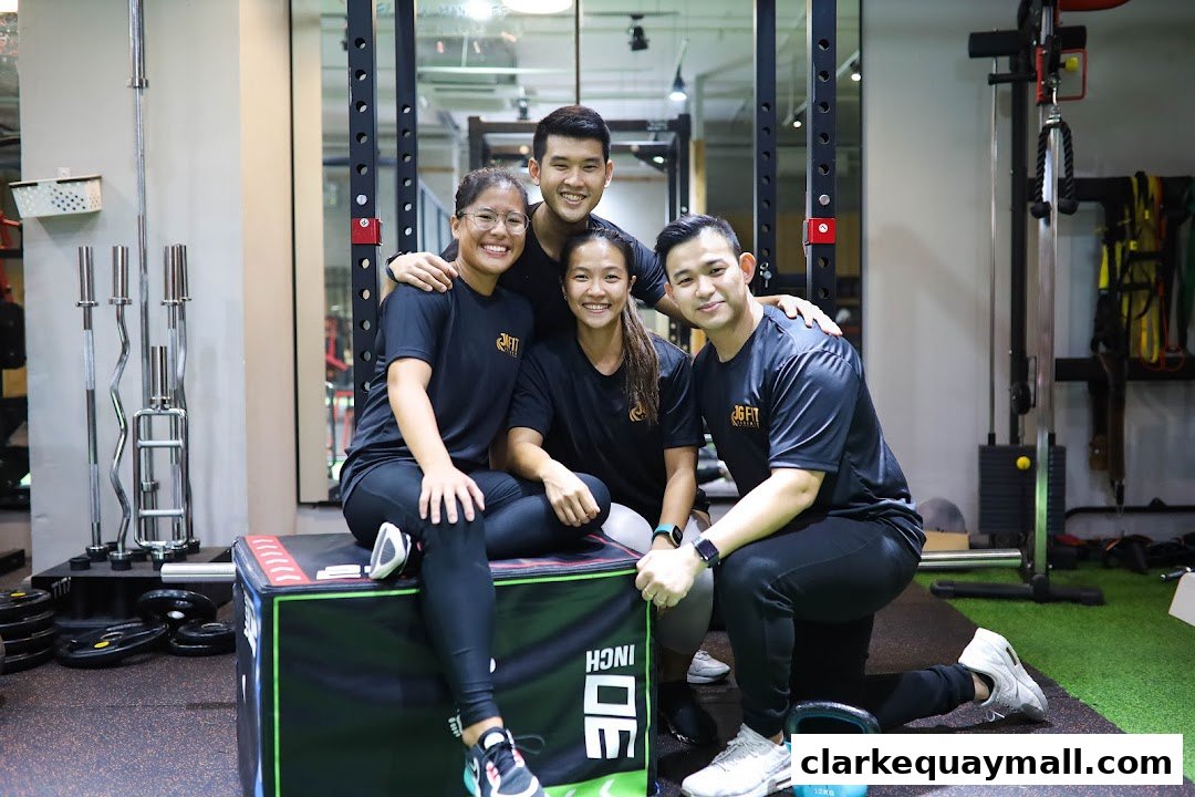 A group of four smiling people in athletic wear posing in a gym.