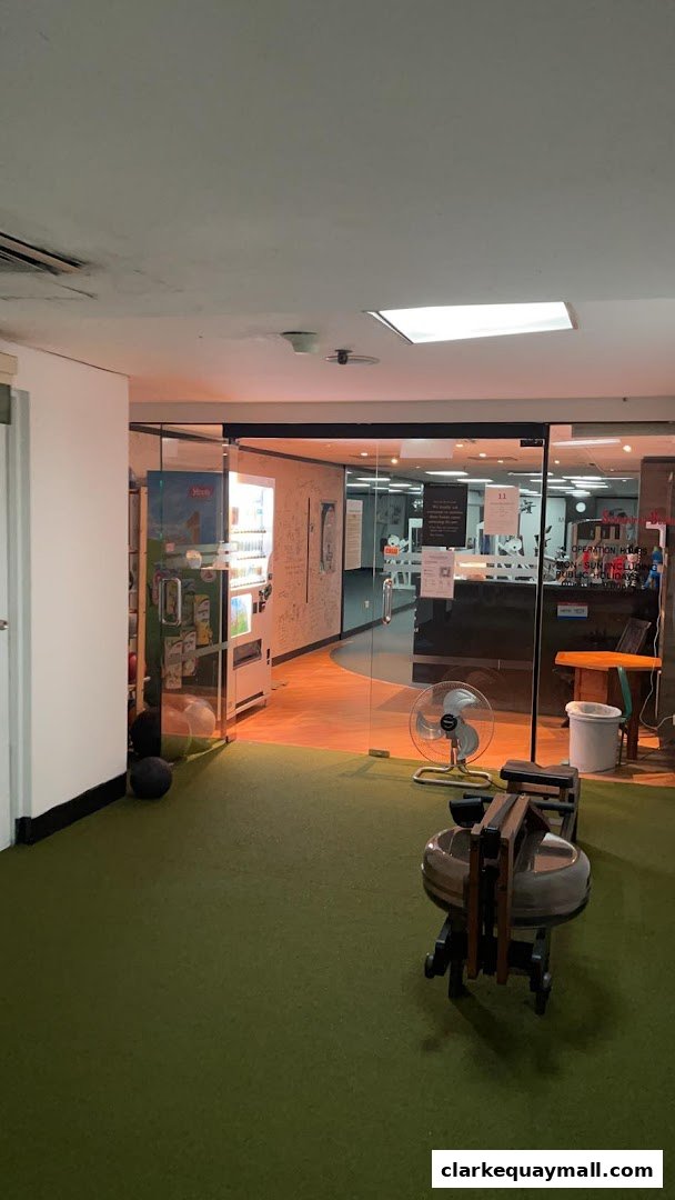 Interior view of a gym with a rowing machine, vending machine, and reception area.