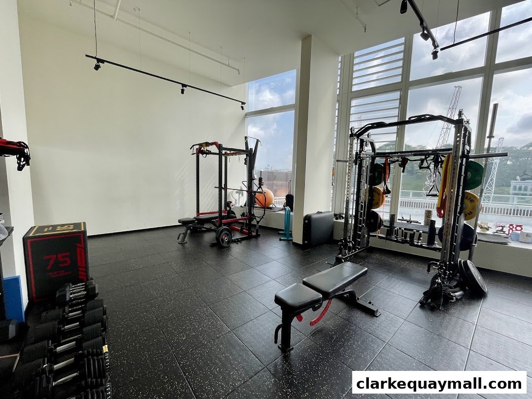 Interior of a modern gym with weightlifting equipment, including racks, benches, and dumbbells.