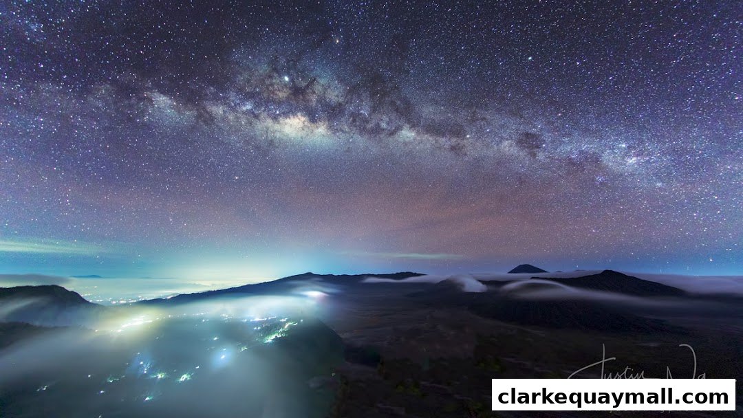 A breathtaking view of the Milky Way galaxy above a misty landscape with city lights.