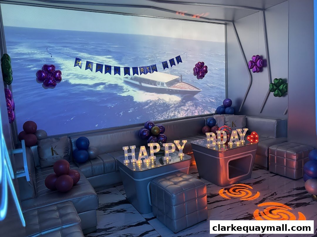 A decorated room with a large screen showing a yacht, balloons, and 'HAPPY BIRTHDAY' lights.