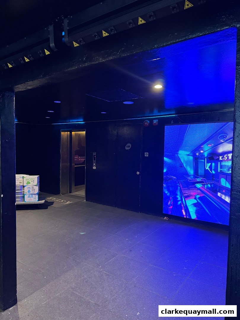 Entrance area with a large LED screen displaying vibrant visuals and a stack of beverage boxes.