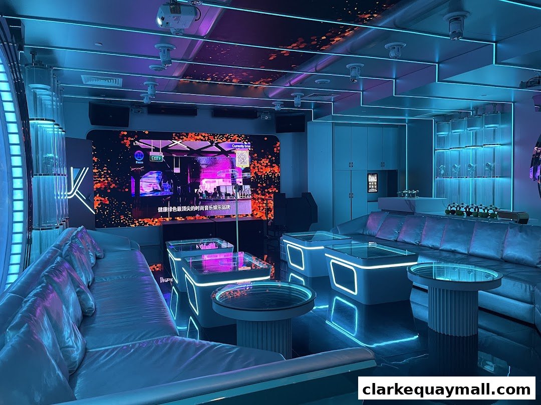 A modern lounge area with neon lights, comfortable seating, and a large screen displaying visuals.