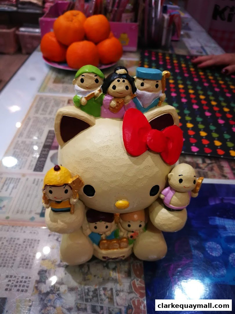 A Hello Kitty figurine adorned with various cartoon characters and a red bow.