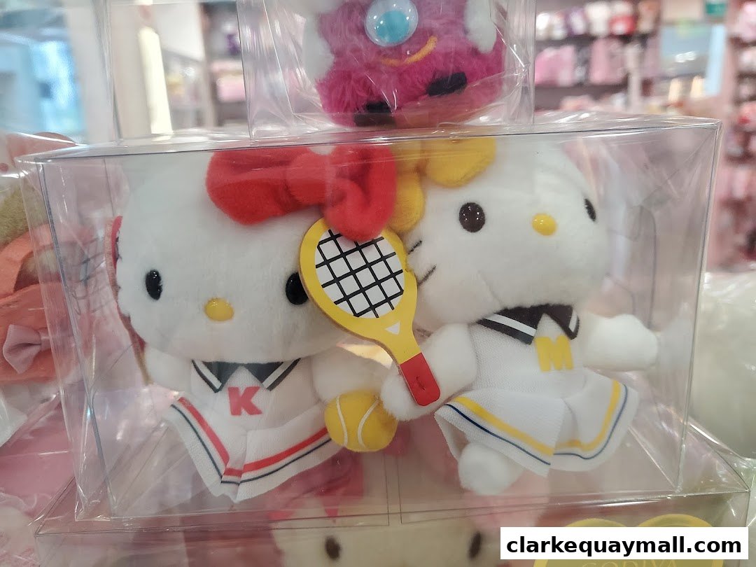 Two Hello Kitty plush toys dressed in tennis outfits, holding a racket and ball.