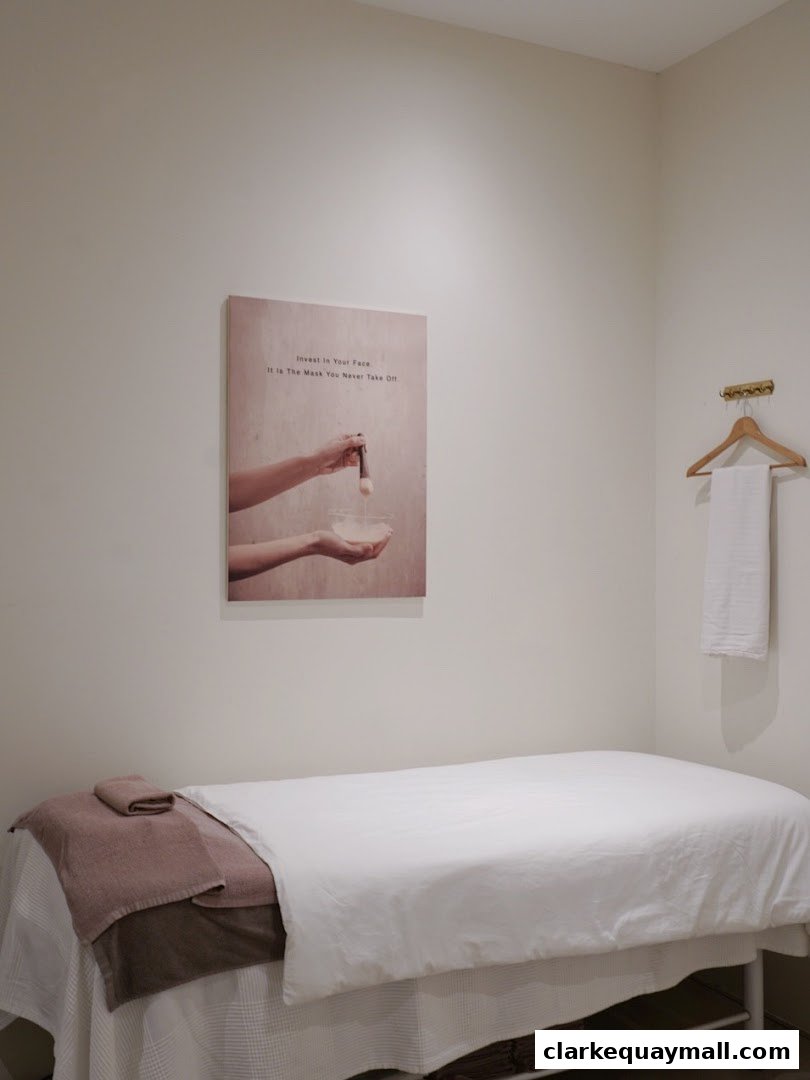 A treatment room with a massage bed, towels, and a framed quote on the wall.