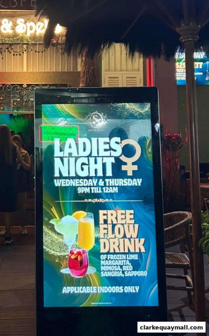 A digital sign advertises Ladies Night with free flow drinks at Kopi & Spells.