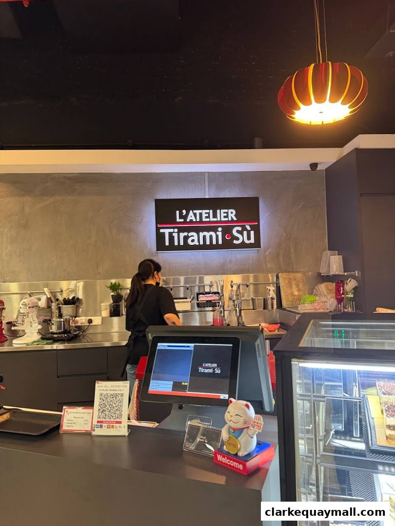 Interior view of L'Atelier Tiramisu with a staff member behind the counter and a display case.