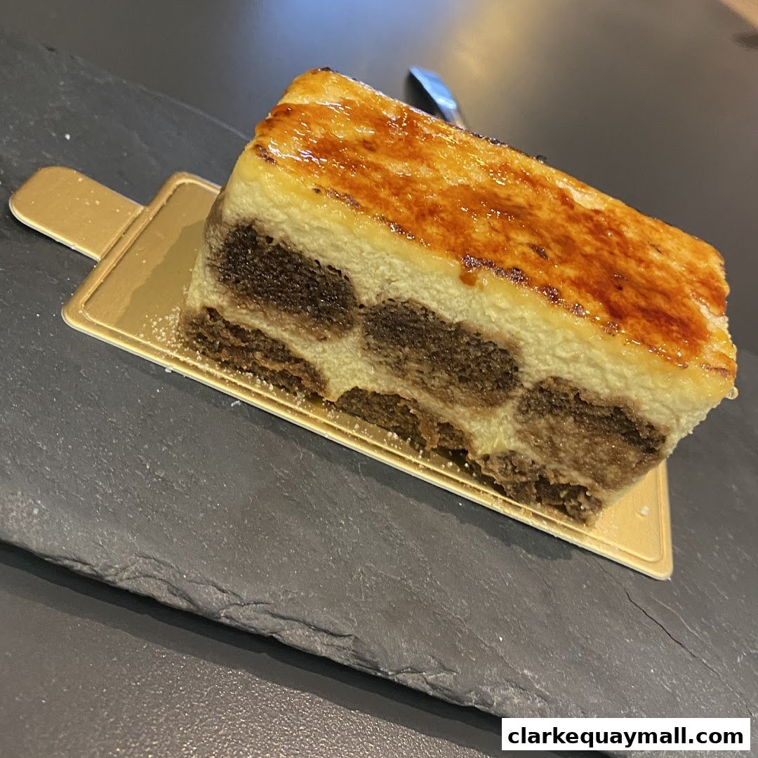 A slice of tiramisu with a caramelized sugar topping on a gold serving tray.